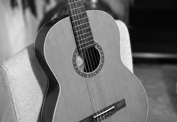 A black-and-white detail of a classical guitar’s rosette and strings