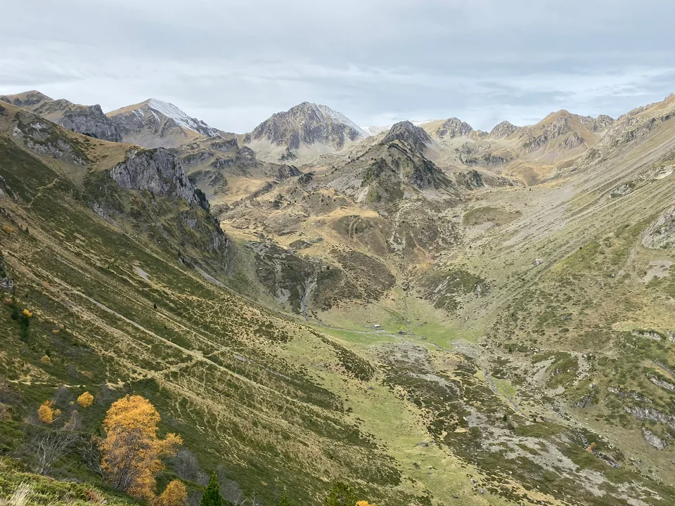Rugged mountain ridges above a broad grassy valley under a pale sky.